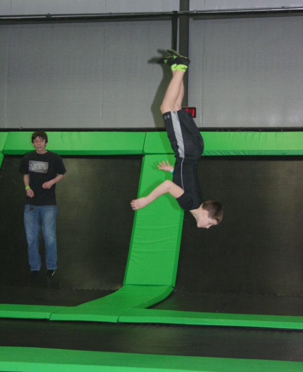 Boy Halfway through Flip on Trampoline at Indoor Fun Park